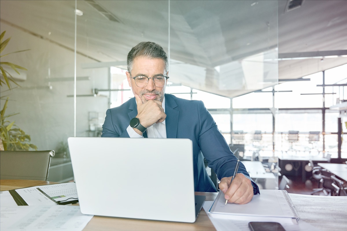 Executive reviewing notes during virtual coaching session at office desk