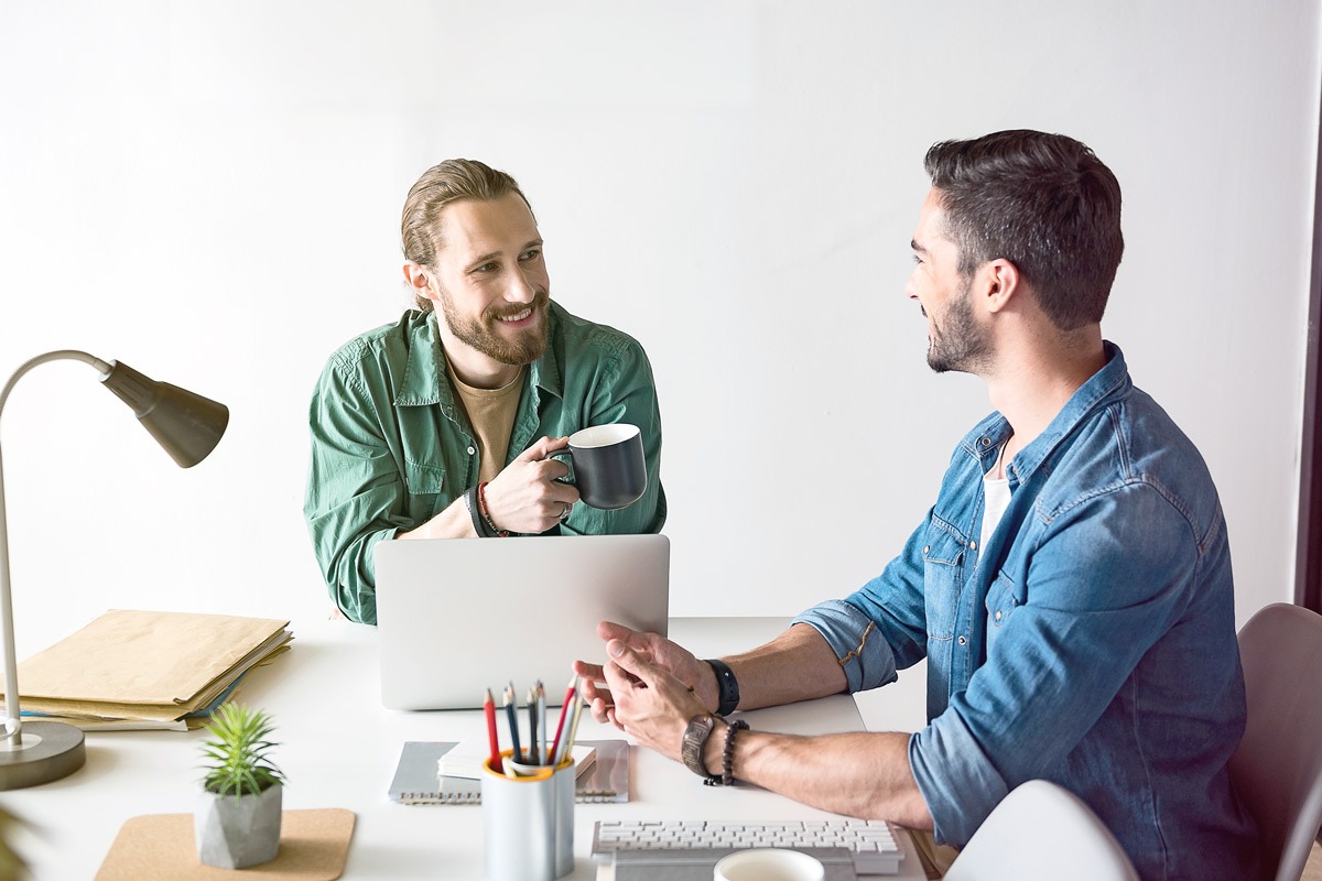 Two professionals having coaching conversation at desk with laptop