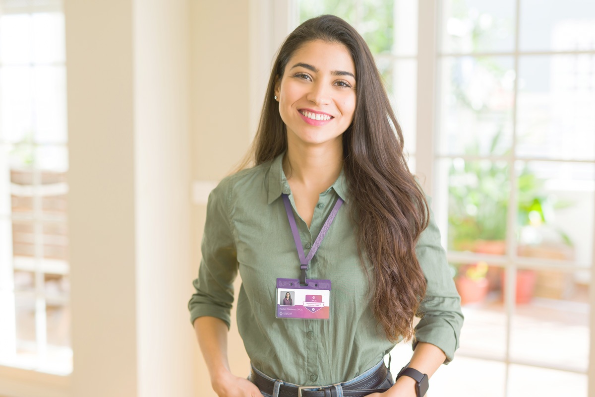 Professional wearing coaching certification badge and smiling indoors